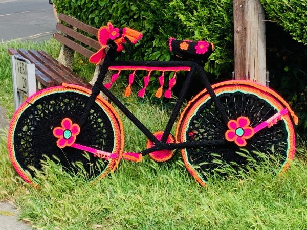 Yarnbomb Sisters - knitted bicycle in mainly pink, orange and black.