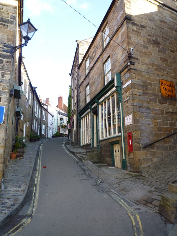 Narrow roadway between stone buildings heading down towards Robin Hood's Bay.