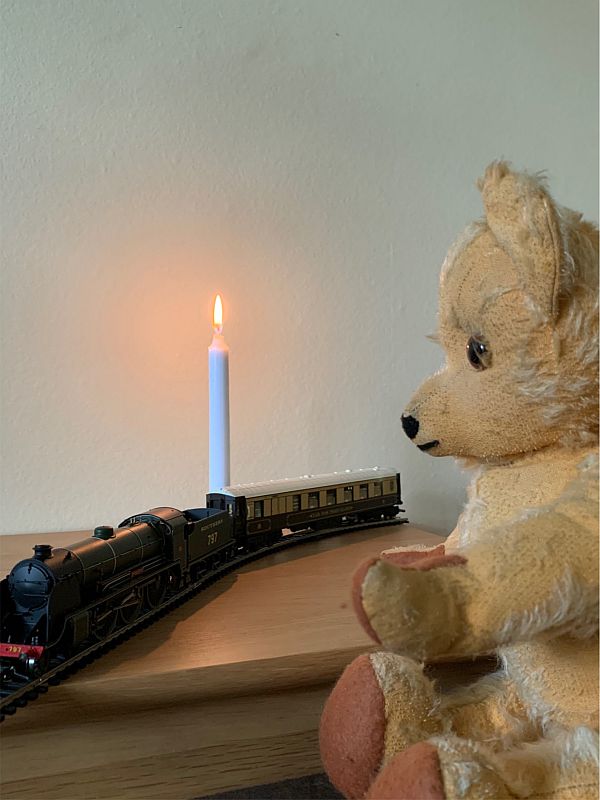 Eamonn waving at a model train with a Pullman Carriage and a candle lit for Diddley.
