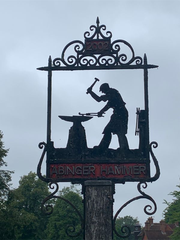 Abinger Hammer village sign, dated 2002. A silhouette of a Blacksmith hammering an anvil.