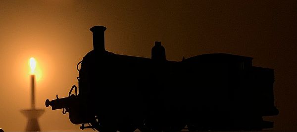 Model steam engine silhouetted in the light of a candle lit for Diddley.