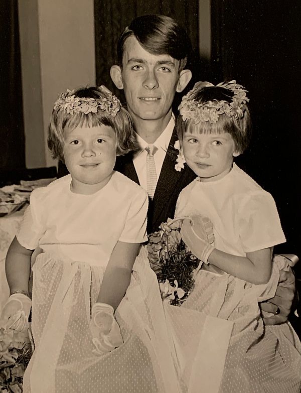 Black & White picture of a man with two young girls dressed as bridesmaids.