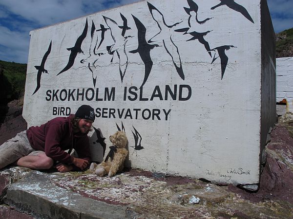 Richard and Bertie sharing a laugh in front of the Skokholm Island Nature Reserve sign.