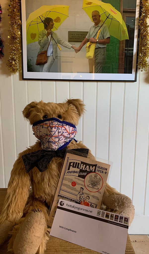 Bertie wearing an Underground map face mask and showing off the "riginal Fulham programme for the very first match Bobby ever attended at Craven Cottage" book.