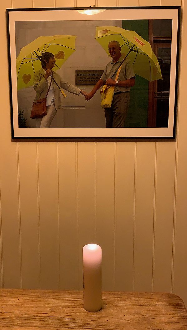 A candle lit for Diddley in front of the "Shredded Wheat" photograph on the wall.