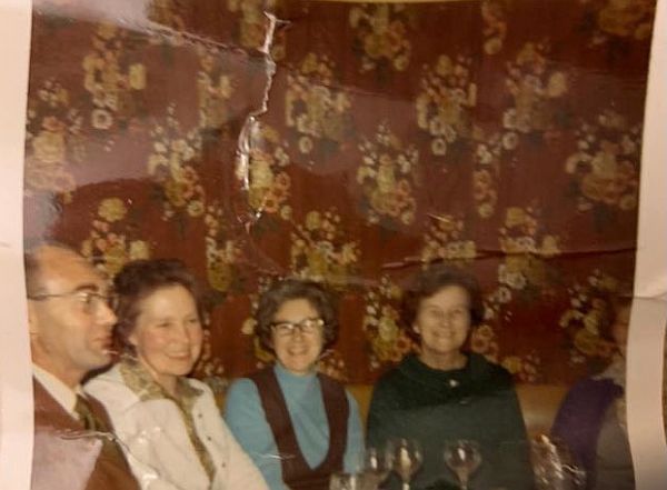 An old and slightly battered family photograph of a man with three ladies.