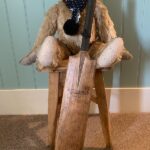 Bertie sat on a tall stook with a cricket bat in front of him.