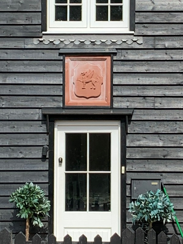 Wooden house in Abinger Hammer with the Wotton Estate Griffin plaque.