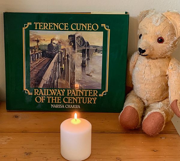 A candle lit for Diddley in front of the Terence Cuneo book "Railway painter of the Century2.