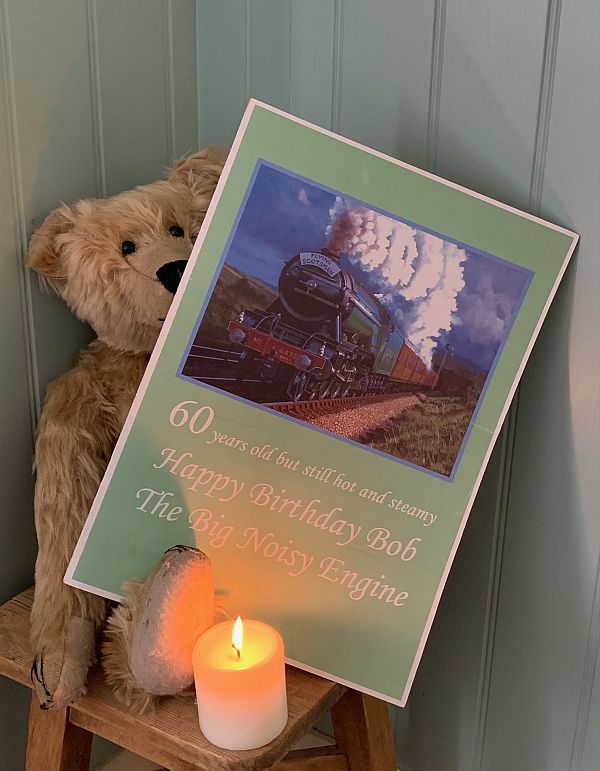 Bertie, with a candle lit for Diddley and the birthday card from Diddley: A picture of the Flying Scotsman and the text "60 years old but still hot and steamy. Haooy Birthday Bob the Bog Noisy Engine".