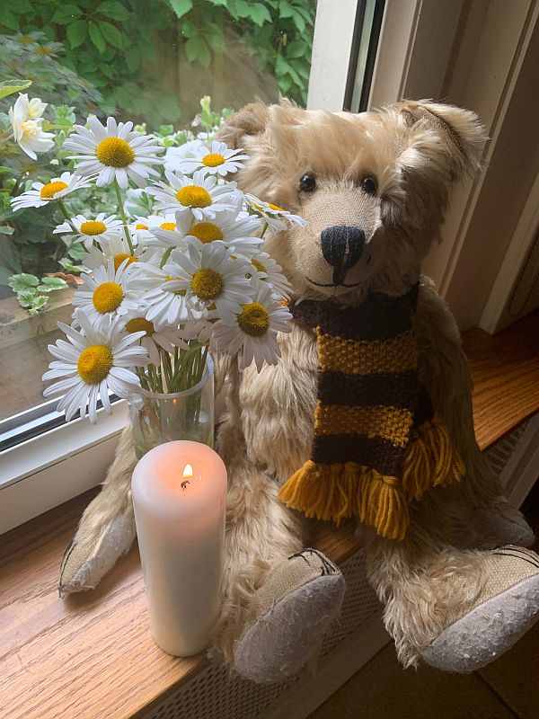 Bertie alongside a vase of Moon Daisies and a candle lit for Diddley in front.