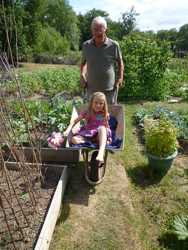 Layla being pushed by Bobby in his wheelbarrow.