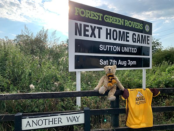 Bertie sat under the sign at Forest Green Rovers for the match with Sutton United. A street sign says "Another Way".