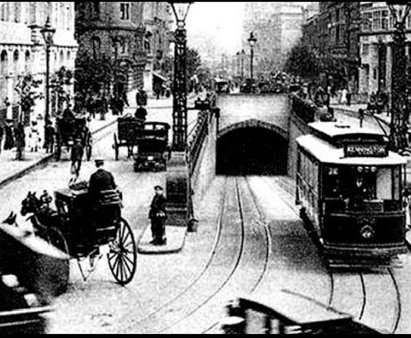 An electric single deck tram emerging from the Kingway Tram Tunnel amidst the horse-drawn carriages of the day.