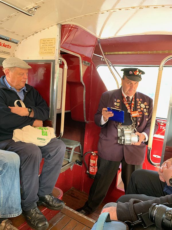 A conductor on the 93 with ticket machine and covered in badges.