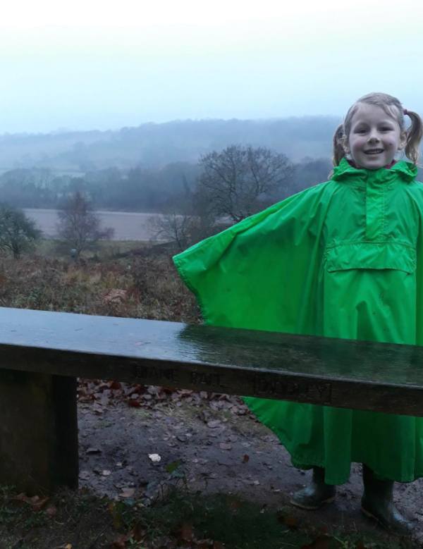 Ava in a green rain poncho at The bench.