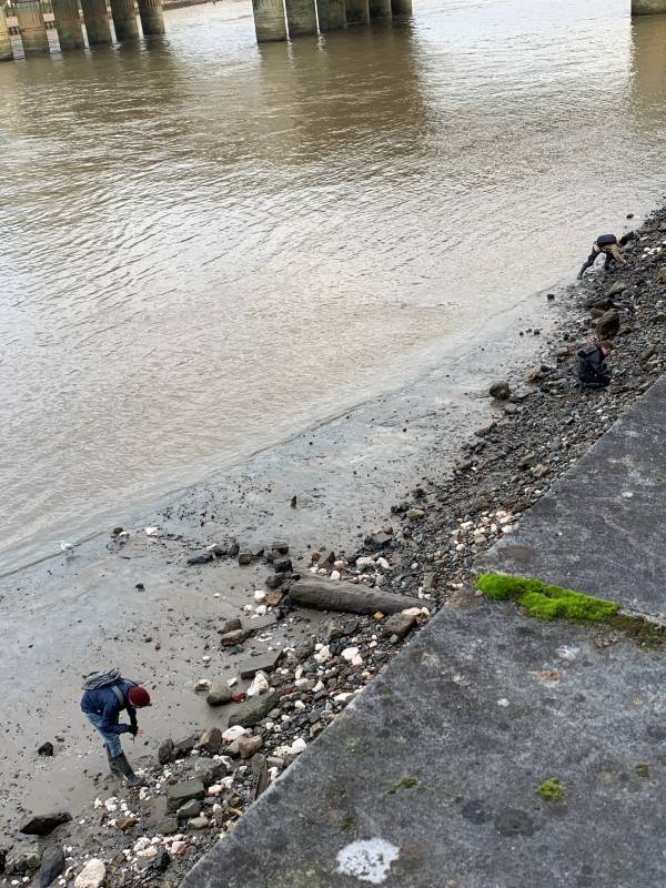 Tide out on the River Thames, with a man looking through what has been washed-up.