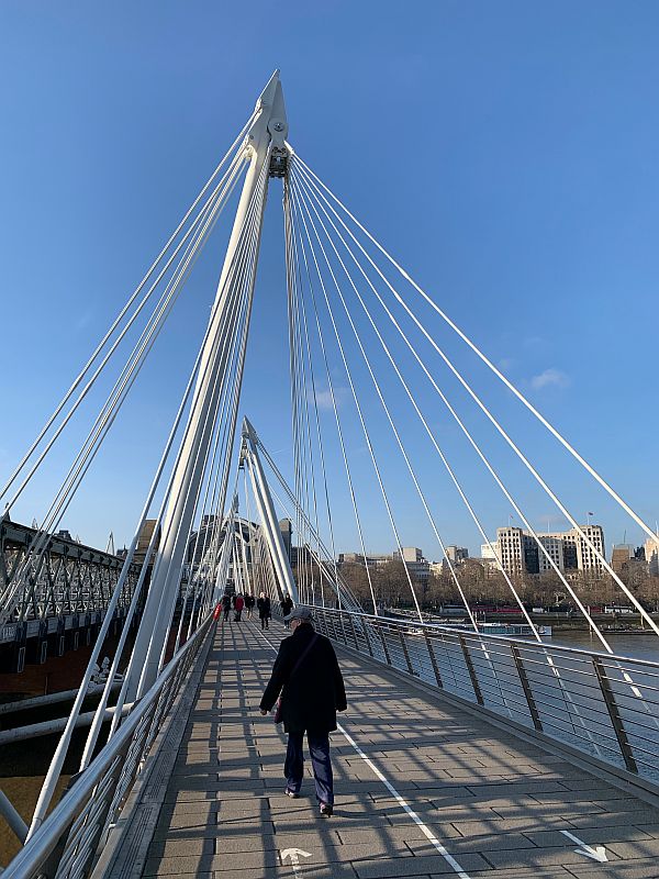 People walking across the Thames on Jubilee Bridge.