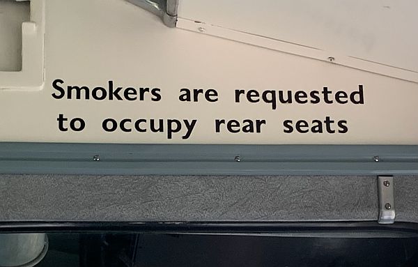 Signage requesting smokers to occupy rear seats.