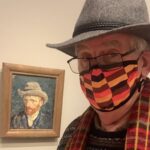 Stress Awareness. Bobby, wearing a multi-coloured facemask, with a self portrait of Van Gogh behind.