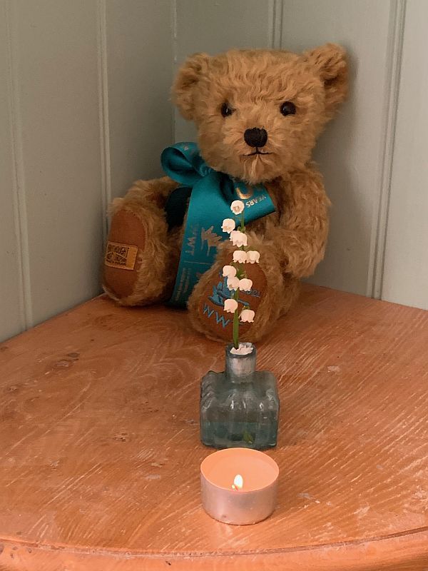 Bewick the Bear with a Lily of the Valley and a candle lit for Diddley.