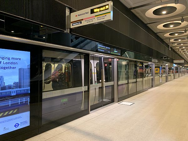 A lightly loaded Elizabeth Line train behind the closed glass barrier at a desserted Paddington platform.