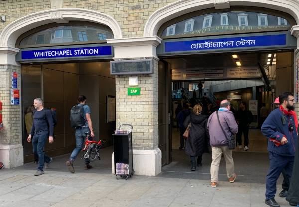 The historic exterior of Whitechapel Station, with the name in both English and Arabic.