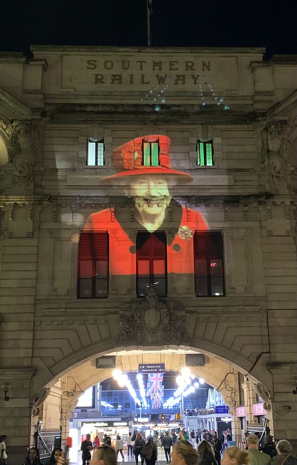 Victoria Station entrance lit up with a picture of the Queen.