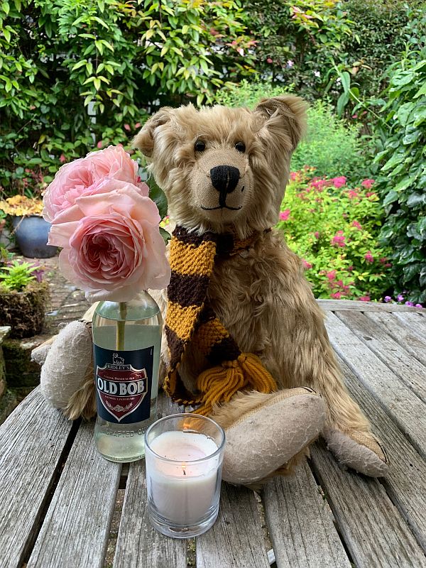 Bertie sat on a table with a candle lit for Diddley and an empty bottle of "Bob" Beer with two pink roses in it.