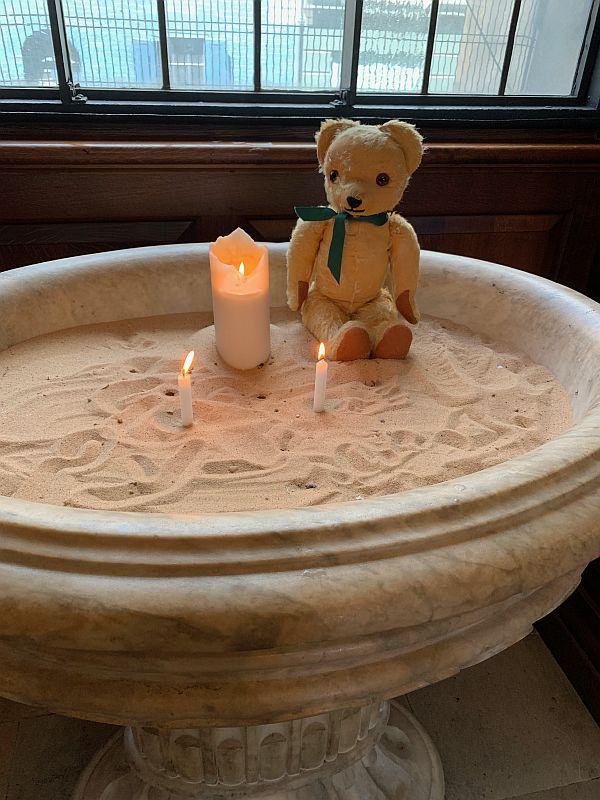 Eamonn sat on the sand in the font at Christ Church, Spitalfields, with two candles - one lit for Diddly and the other for friend Mick.