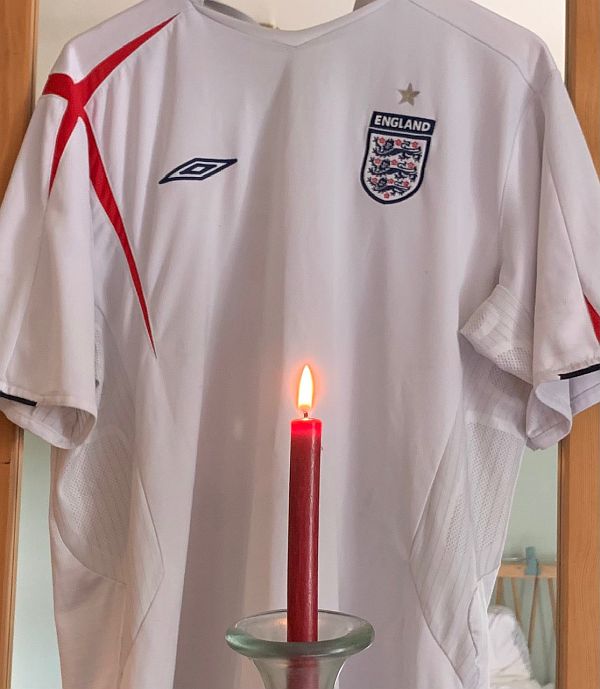 A red candle lit for Diddley in front of Bobby's 2005 England shirt.