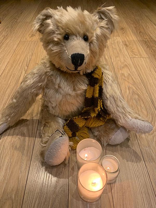 Bertie, wearing his Sutton United scarf. There are three candles in jars in front of him.