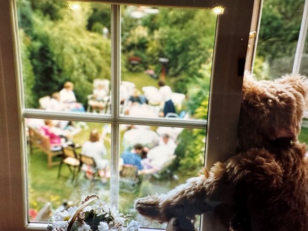 Bertie looking out of an upstairs window at people sat in a circle having a party in the garden. Remembering Bobby - one year on.
